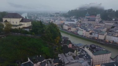 Avusturya 'nın Salzburg şehrinden geçen Salzach Nehri' nin havadan görünüşü. Sis yavaşça dağılıyor, şehir manzarasını ve kiliselerini ortaya çıkarıyor..