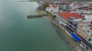 Turistler Yunanistan 'daki Paralia Katerinis plajı boyunca geziyorlar. Oteller ve restoranlar da dahil olmak üzere binalar Ege Denizi kıyısını kaplıyor.