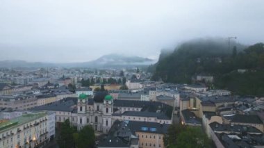 Hava görüntüleri Salzburg 'un tarihi şehir merkezini gösteriyor. Alçak bulutlar ikonik simgeler ve Salzach Nehri üzerinde sürükleniyor. Sabah sisi ve şehir cazibesinin büyüleyici bir manzarası var..