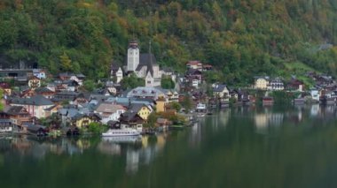 Feribot, Hallstatt 'ın sakin gölünü geçiyor. Yansıması, suların kenarındaki büyüleyici mimari ve renkli evleri yansıtıyor..