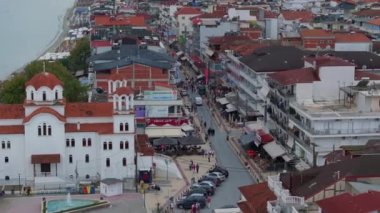 Yunanistan 'ın Paralia Katerinis limanında turistler yürüyor. Sahilde beyaz bir Doğu Ortodoks kilisesi görülebilir. Arka planda Ege Denizi var..