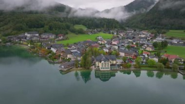 Alçak bulutlar Fuschlsee gölünün durgun yüzeyine yansıyor, Fuschl am 'ın renkli binalarını yansıtıyor..