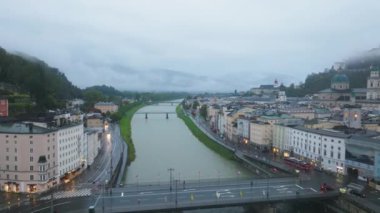 Salzburg şehir merkezinin şehir manzarası ve Salzach Nehri şehir manzarasından akıyor. Şehir manzarası sisli bir sabahta sokak ışıklarıyla aydınlanır..