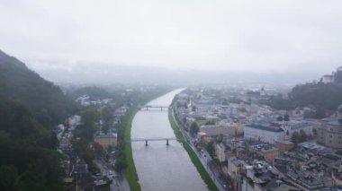 Avusturya, Salzburg 'un hava manzarası Salzach Nehri, Hohensalzburg Kalesi ve bulutlu bir gökyüzü altında büyüleyici bir mimari ile şehir manzarasını gözler önüne seriyor..