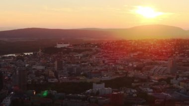 Bratislava, Slovakya, şehri sıcak altın renginde yıkayan nefes kesici bir günbatımına sahip. Akşam gökyüzü canlı bir ekrana dönüşerek şehir manzarasını ve mimarisini vurguluyor..