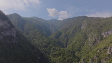 Yunanistan 'ın Olimpos Dağı' ndaki verimli bir vadinin orman tepelerinden akan güneş ışığı, canlı yeşillik ve yüksek dağlarla dolu sakin ve güzel bir manzara yaratır..