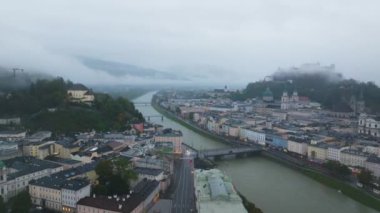 Sisin yavaşça dağıldığı Salzburg şehrinin hava manzarası. Salzach Nehri şehir merkezinden akıyor..