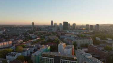 Altın güneş ışığı, gün doğumunda Bratislava silueti sıcak bir parıltı yaratıyor, sakin bir sabah atmosferinde şehirleri sersemleten mimari ve canlı renkleri vurguluyor..