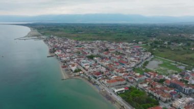 Kamera, Ege Denizi kıyısındaki popüler bir sahil beldesi olan Paralia Katerinis 'in uzun kumlu plajını ve hareketli gezinti alanlarını gösteriyor..