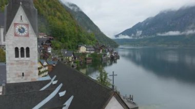 Geleneksel Avusturya mimarisi ve Protestan kilisesinin Salzkammergut bölgesindeki Hallstattersee Gölü 'nün sakin sularına yansıttığı Picturesque Hallstatt köyü..