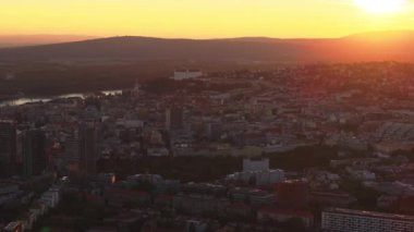 Bratislava, Slovakya 'nın başkenti, gün batımının sıcacık ışığında parlıyor. Tuna Nehri şehirde süzülüyor, akşam gökyüzünün canlı renklerini yansıtıyor..