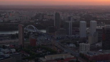 Hava manzarası, Tuna Nehri ve Apollo Köprüsü 'nü gösteren Bratislava ufuk çizgisini vurguluyor. Hepsi de parlak renklerle dolu çarpıcı bir günbatımında parlıyor..