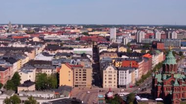 Helsinki 'nin merkezi çatılarının hava manzarası ve çarpıcı Uspenski Katedrali. Sahne, güneşli mavi gökyüzünün altında canlı bir şehir manzarası yakalıyor, mimari güzelliği vurguluyor..