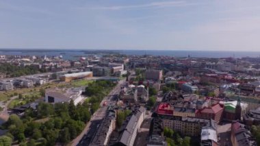 Helsinki, Finlandiya 'da gökyüzü bulutlarla dolu güneşli bir gökyüzünün altında şehirlerin olağanüstü mimarisini, renkli binaları ve yeşil parkları gösteren hava manzaraları ön plana çıkıyor..
