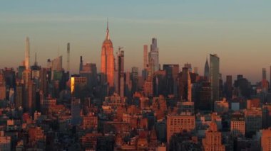 Sıcak güneş ışığı Empire State Binası 'nı ve Manhattan şehir merkezindeki gökdelenleri yıkıyor. Güneş canlı New York şehrinin silueti üzerinde yükseliyor.