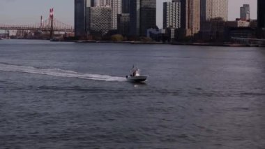 Sahil Güvenlik teknesi Doğu Nehri 'nden geçiyor. Manhattan ve Queens ilçeleri arasında Roosevelt Adası' nı geçiyor. Roosevelt Adası Köprüsü ve Manhattan gökdelenleri.