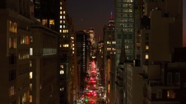 Arabalar gece vakti lüks binaları aydınlatan hareketli bir Aşağı Manhattan, New York caddesinde yol alırlar. Şehir sahnesinin dinamik atmosferi büyüleyici bir görsel deneyim yaratır..