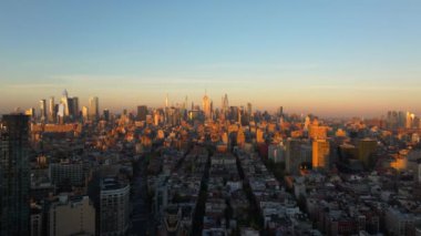 New York 'u çevreleyen sıcak güneş ışığının kuşbakışı manzarası Manhattan şehir merkezindeki binalar, altın saat boyunca gökyüzünü canlı renklerle boyuyor..