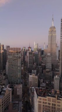 Dikey paneller, Empire State Binası 'nın gün batımında New York şehrinin ufuk çizgisinde zarafetle yükseldiğini gösteriyor..