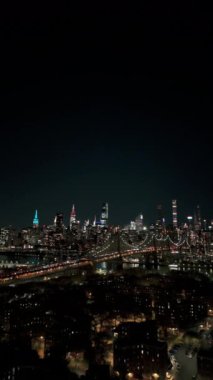 Queens ve Manhattan 'ı East River' a bağlayan Queensboro Köprüsü 'nü görüntüler. Şehir panoramasının karanlık bir zeminine karşı gece trafiği binaları gösteriyor.