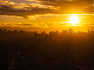 Manila 'da altın saat, şehir gökdelenlerinin arkasında güneş batar, şehir manzarasına güzel bir turuncu parıltı yayar..