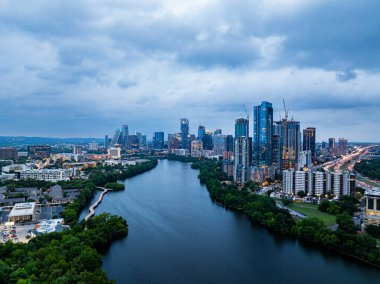 Aerial view of Austin, Texas skyline at dusk, showcasing modern skyscrapers reflecting on the Colorado River under a dramatic cloudy sky. clipart