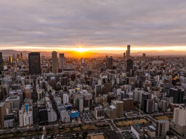 Stunning aerial view of Osaka, Japan, skyline at sunrise, showcasing modern skyscrapers, urban structures, and the beautiful warm tones of early morning light. clipart