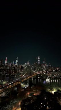 Queens ve Manhattan 'ın gece aydınlık siluetinin dikey videosu, Queensboro Köprüsü ve Doğu Nehri havadan görülebiliyor..