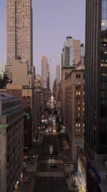 Manhattan şehir merkezinin dikey hava manzarası. Arka planda Empire State Binası olan bir caddeden aşağı doğru giden sarı taksiler..