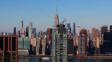 New York şehrinin gökdelenleri East River 'ı gösteriyor, ikonik Manhattan gökdelenleri Empire State Binası arka planı, Queens modern konut binaları ön plan.
