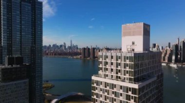 New York şehrinin dinamik gelişimini gösteren ikonik Manhattan silueti arka planına sahip doğu nehri ve yerleşim binalarını görüntüler..