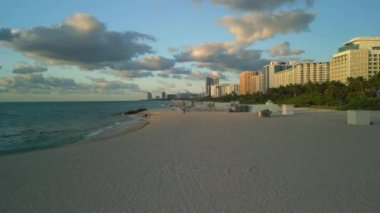 Gün batımında Miami Sahili 'nin havadan görünüşü sakin dalgalar ve altın ışıkla sakin kıyı şeridini yakalıyor. Çok az sahil sakiniyle sakin bir akşam atmosferi sergiliyor..