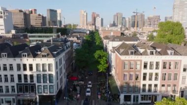 Rotterdam 'da yüksek açılı ağaç manzaralı bir cadde, tarihi binalarla modern gökyüzü ve şehir yaşamını yakalıyor..