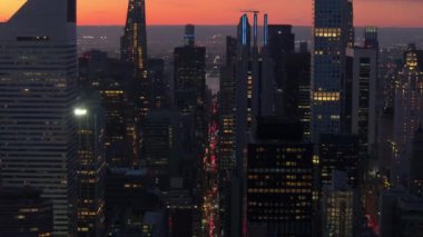 Güneş Manhattan 'da batarken, turuncu ve mavi gölgeler gökyüzünü boyuyor. Yükselen gökdelenler, aşağıdaki hareketli şehir manzarasının üzerine sıcak bir parıltı saçıyor..