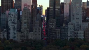 Günbatımı, New York şehrinin ufuk çizgisine sıcak bir ışık saçıyor. Aydınlatılmış gökdelenler ve hareketli sokaklar canlı bir şehir manzarası yaratıyor..