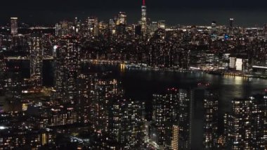 Aşağı Manhattan ve Doğu Nehri 'nin geceleri hava manzarası. Kamera New York gökdelenleri üzerinde hareket ediyor. Şehir ışıklarının çarpıcı manzarasını sunuyor..