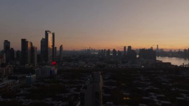 Günbatımında Long Island Citys modern mimarisini yakalıyor. Manhattan adası ve Doğu Nehri arkaplanı New York şehrinin ufuk çizgisini yükseltiyor..