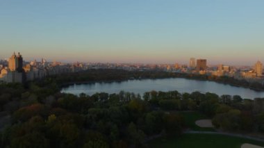 Havadan alınan görüntüler, New York şehrinin silueti tarafından çerçevelenen ve günbatımında sakin bir şehir manzarası yaratan Central Park rezervuarını ve çeşmesini vurguluyor..
