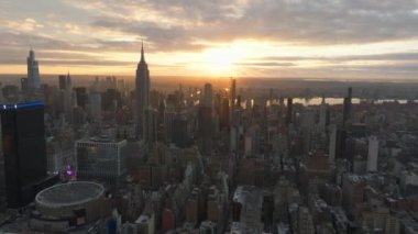 Hava görüntüleri, New York şehrinin gökdelenlerini aydınlatan, ikonik gökdelenleri ve işlek sokakları sıcacık bir parıltıyla aydınlatan, çarpıcı bir sabah manzarası oluşturan güneşin doğuşunu yakalıyor..