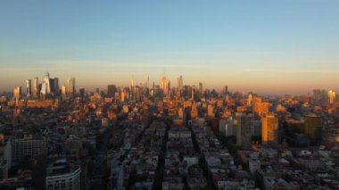 Sıcak güneş ışığı Manhattan şehir merkezini ve New York şehrinin ufuk çizgisini sarar. Güneş ufukta batarken yükselen gökdelenlerden uzayan gölgeler yaratır..