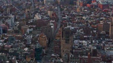 Yoğun bir New York caddesinin üzerinden geçen kamera alçak katlı binaların ve uzaktaki Doğu Nehri 'nin tepelerini gösteriyor..
