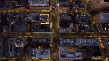 New York 'taki Manhattan sokaklarının kuş bakışı görüntüsü gece aydınlanıyor, yukarıdan canlı şehir hayatı ve mimarisi parlayan ışıklar ve hareketli aktivitelerle sergileniyor..