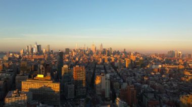 New York 'ta Manhattan şehir merkezindeki sıcak güneş ışığının kuşbakışı görüntüsü. Hudson Nehri üzerinde güneş batar, gökyüzü boyunca canlı renkler ve şehir manzarası.
