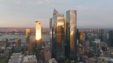 Sıcak akşam ışığı Manhattan şehir merkezindeki modern gökdelenleri yıkıyor, altın saat boyunca cam cephelerde çarpıcı yansımalar yaratarak, kentsel ufuk çizgilerini güzelleştiriyor..