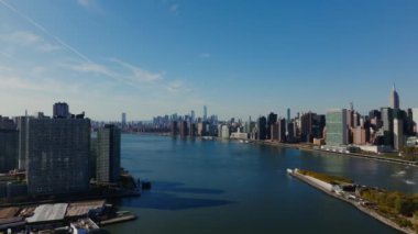 Gökyüzü, temiz mavi gökyüzünün altında yükselen ikonik Manhattan gökdelenleriyle Roosevelt Adası ile Doğu Nehri 'ni vurguluyor..