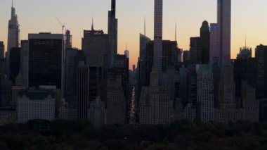 Manhattan şehir merkezindeki gökdelenler gün batımında gölgelerden yükselirken Central Park verimli bir zemin sağlıyor..