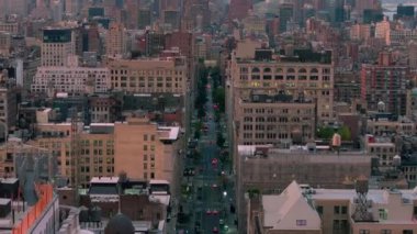 New York 'un hareketli caddeleri boyunca uçan hava manzaralı araçlar. Önde gelen binalar ve çatılar manzarayı doldurarak, akşam saatlerinde kentsel manzarayı vurguluyor.