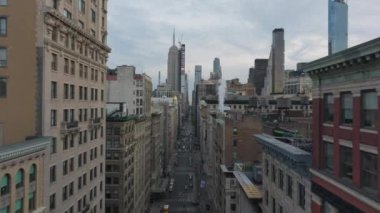 New York 'ta işlek bir caddede kamera var. Kanalizasyondan buhar yükseliyor ve sarı taksiler caddede ilerliyor..