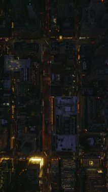 Manhattan, New York 'ta geceleri hava görüntüleri sokakları ve simgesel işaretleri yavaş çekimde yakalıyor. Dikey bir videoda canlı şehir atmosferi ve canlı gece hayatı.