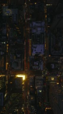 Dikey panoramik görüntüler Manhattan, New York 'u gece ağır çekimde çeker. Parlayan sokaklar ve hareketli trafik dinamik şehir ortamındaki gökdelenler arasında.